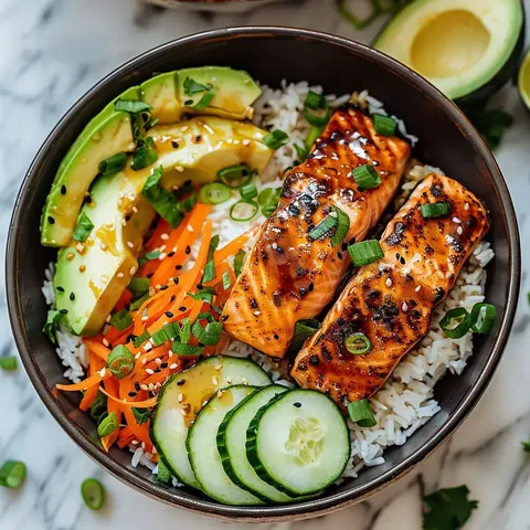 Bol gourmand avec saumon grillé, avocat, carottes, concombres et ciboule.