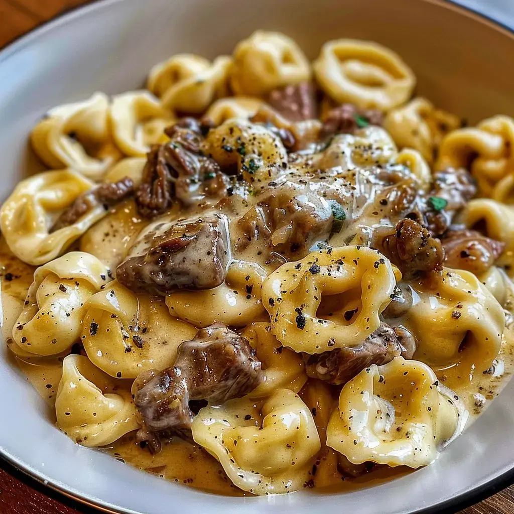 Un bol de tortellinis onctueux avec de la viande bœuf dans une sauce crémeuse et des légumes croquants, assaisonné avec quelques épices.