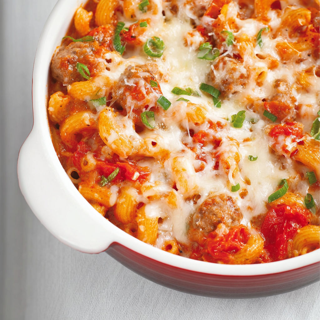 Bol contenant des pâtes aux tomates et aux saucisses italiennes, avec une belle surface gratinée.