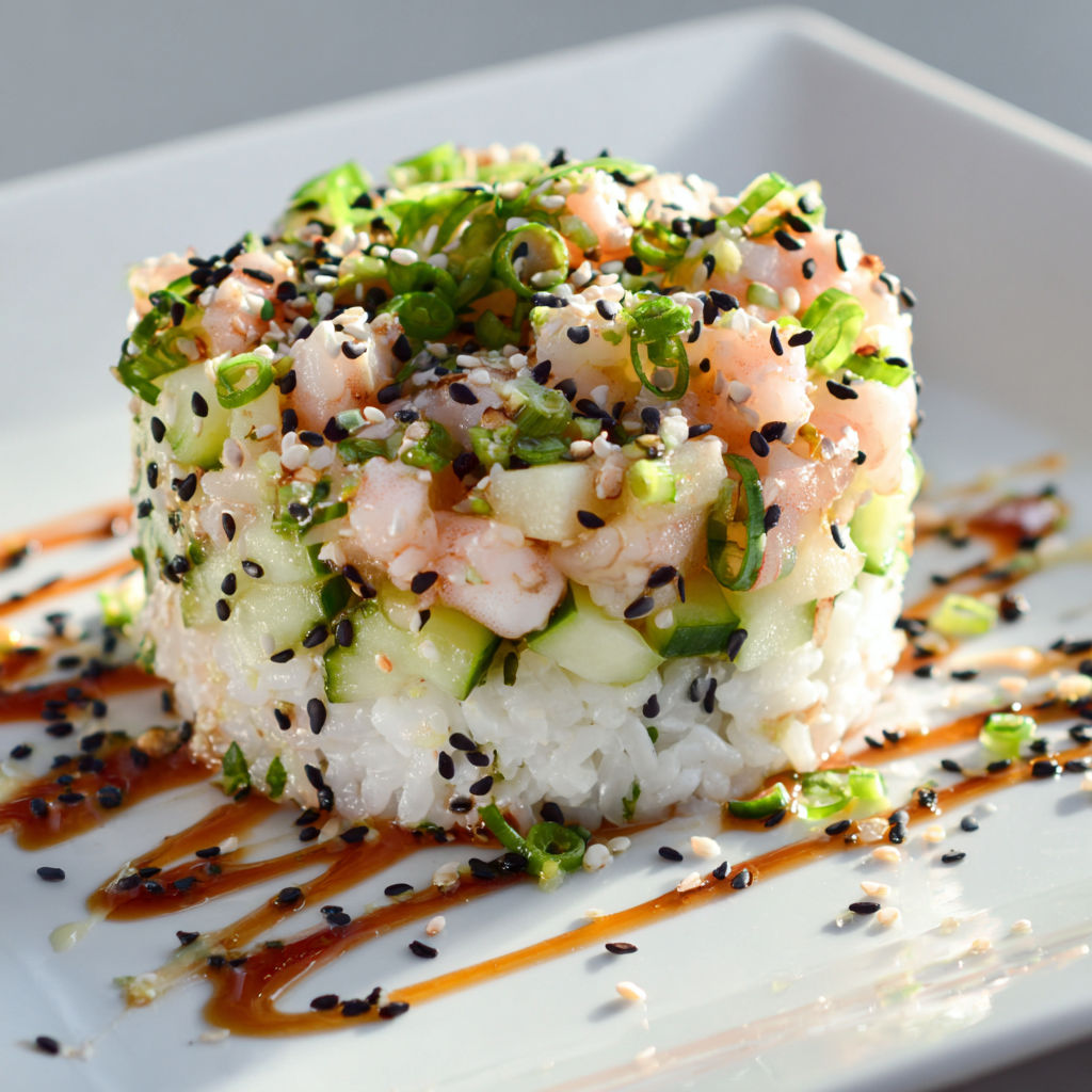 Un plat de salade avec des crevettes nordiques et une présentation élégante sur un plateau en verre.