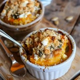 Petits plats de gratin doré au potiron et fromage servis sur une planche en bois.