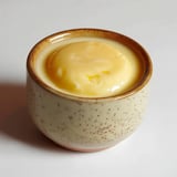 Un bol céramique rempli d'une crème pâtissière jaune appétissante.