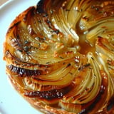 Appétissante Tarte tatin aux endives avec une croûte feuilletée dorée sur un plat blanc.