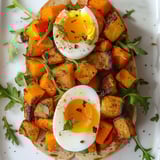 Un pain garni de légumes rôtis et d’œufs, accompagné de roquette, présenté sur une planche en toute simplicité.