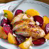Poulet mariné servi avec des oranges, des betteraves rôties et des radis colorés.
