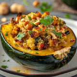 Une courge garnie de quinoa, cheddar et herbes sur un plateau, avec des arachides en décoration.