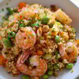Un bol coloré rempli de riz frit, crevettes et edamame, un plat parfumé et appétissant.