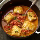 Un plat gourmand de lotte cuisinée à l'Armoricaine, joliment présenté dans un bol.