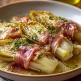 Un plat savoureux d'endives au jambon nappées d'une sauce blanche.