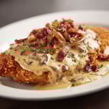 Assiette d'escalope avec sauce reblochon et lardons dorés.