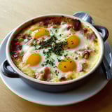 Ramequin gourmand avec des œufs cocotte et du fromage gratiné sur une table.