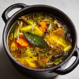 Bouillon maison préparé avec feuilles de poireaux et épluchures dans un bol noir.