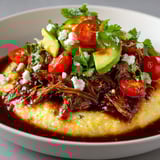 Plat chaleureux de polenta moelleuse et bœuf tendre effiloché, agrémenté d'accompagnements frais.