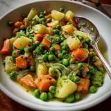 Un mélange savoureux de légumes tendres, carottes, petits pois, pommes de terre et haricots verts, servi dans un bol.
