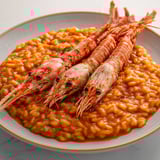 Un plat de langoustines servies avec un riz crémeux et des touches de couleur.