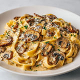 Assiette de pâtes avec champignons, ail et fromage servie simplement à table.