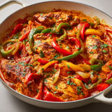 Une belle poêlée de poulet aux poivrons avec coulis de tomates, servie dans un plat en acier.