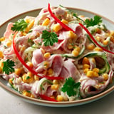 Ensemble croquant de tagliatelles de concombre, jambon et maïs pour une salade légère.