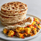 Un plateau avec des tortillas moelleuses maison, présentées avec sauce et légumes.